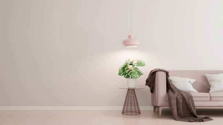 Glad gestuukte lichte wand met roze hanglamp, plant en bank