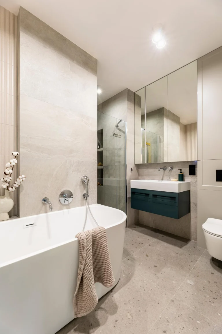Badkamer met grote natuursteenlook wandtegels, vrijstaand bad en inloopdouche