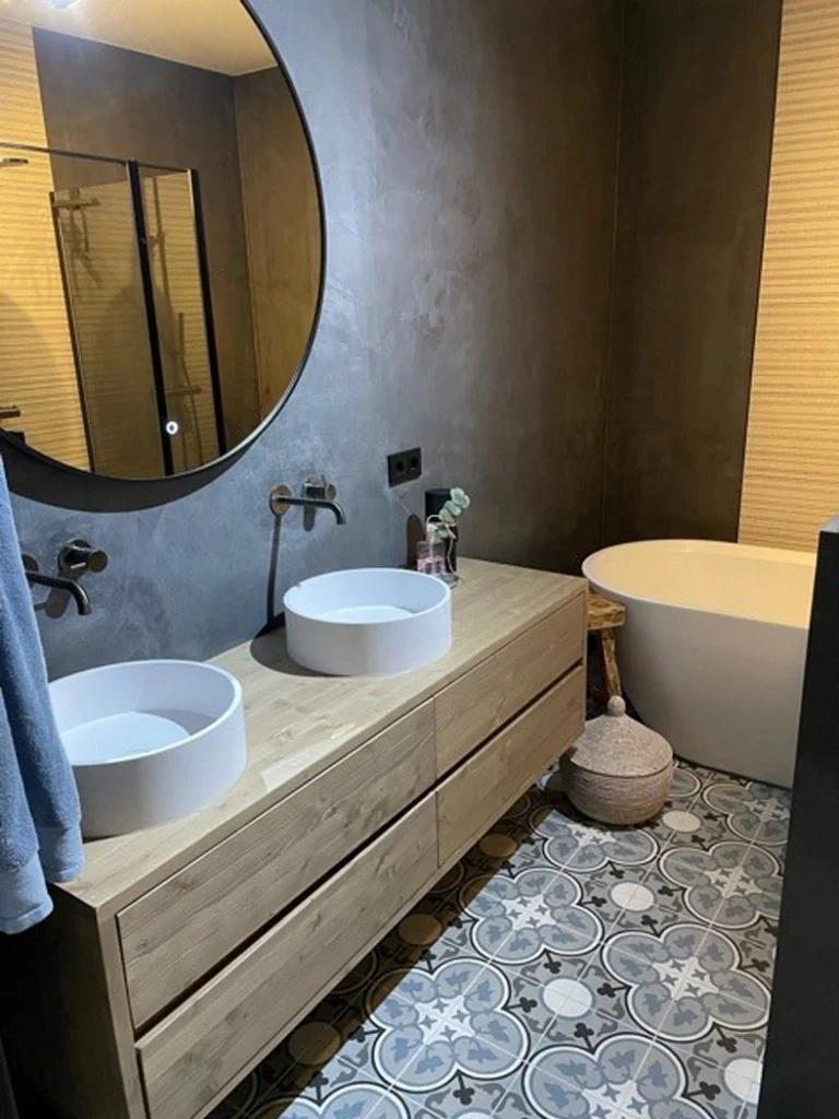 Betonlook badkamer met donkere wanden, dubbele waskom en patroontegels op de vloer